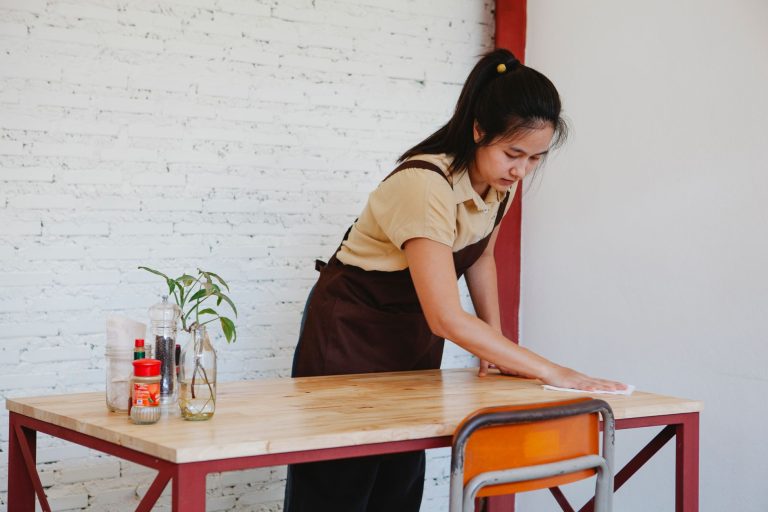 Cleaner wiping a desk surface during a small office cleaning visit